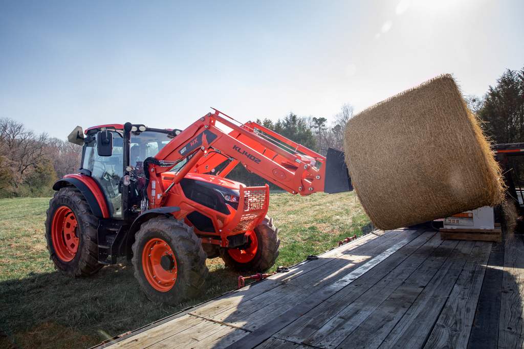 KIOTI HX 1402 utility tractor lifting a hay bale