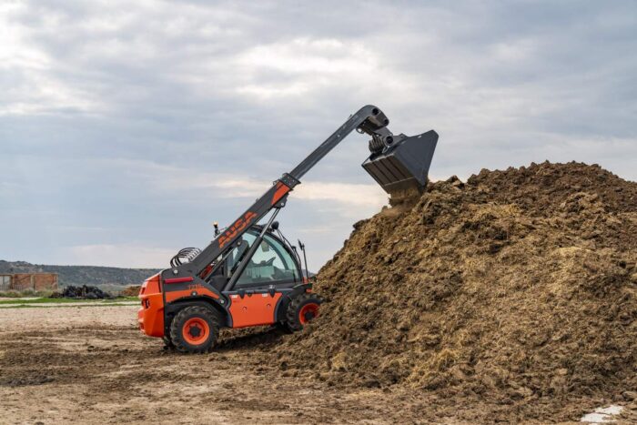 AUSA compact telehandler digging in the dirt 