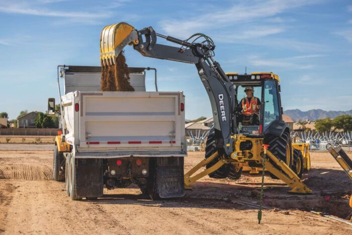 John Deere backhoe lifting spoils into the back of a dump truck
