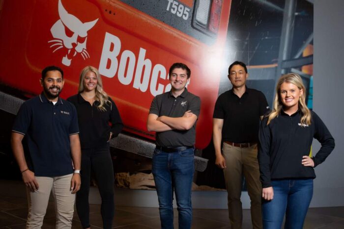 bobcat-employees standing in front of a bobcat sign 