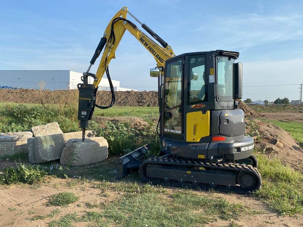 New Holland E42D mini excavator with hammer attachment near rocks