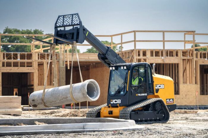 JCB 4TS Teleckid track loader holding up a piece of concrete pipe  
