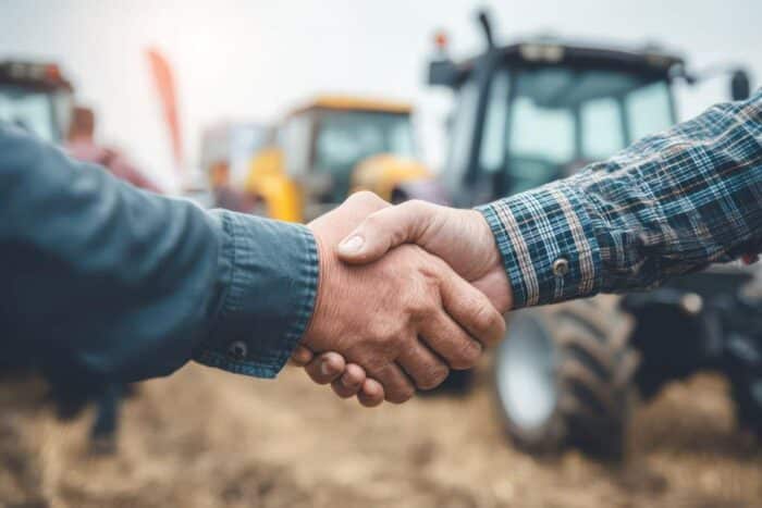Deal Between Businessman and Farmer. Agribusiness handshake symbolizing a business deal or agreement between a businessman and a farmer for equipment sale. AI generated