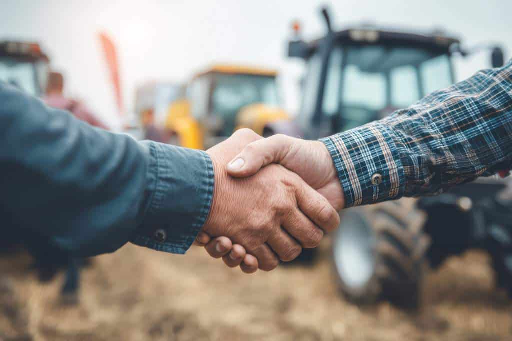 Deal Between Businessman and Farmer. Agribusiness handshake symbolizing a business deal or agreement between a businessman and a farmer for equipment sale. AI generated