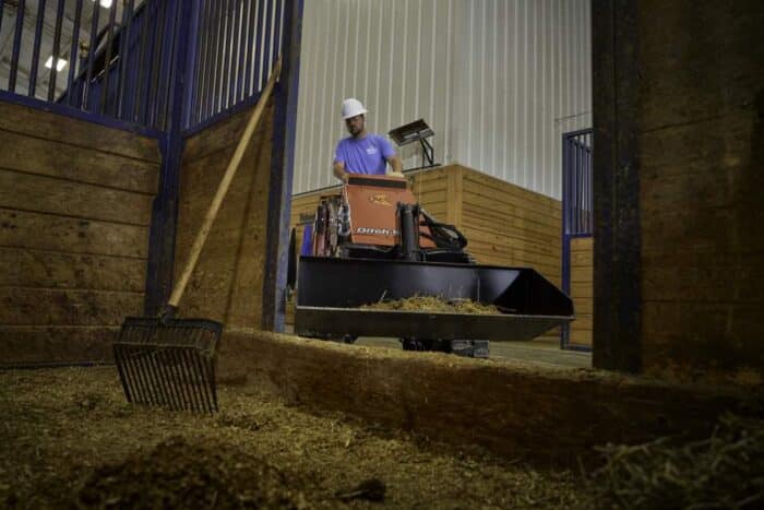 Ditch Witch SK1000 stand on skid steer moving past a doorway