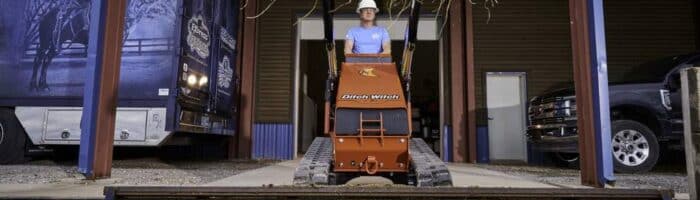 Ditch Witch's SK1000 Stand-On Skid Steer lifting dirt and hay