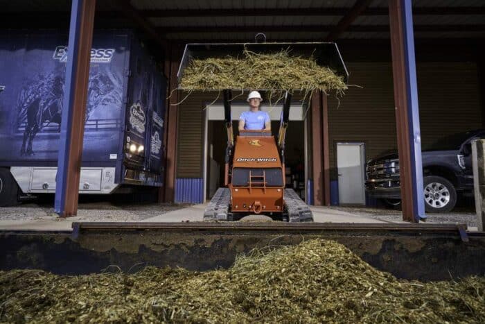 Ditch Witch's SK1000 Stand-On Skid Steer lifting dirt and hay