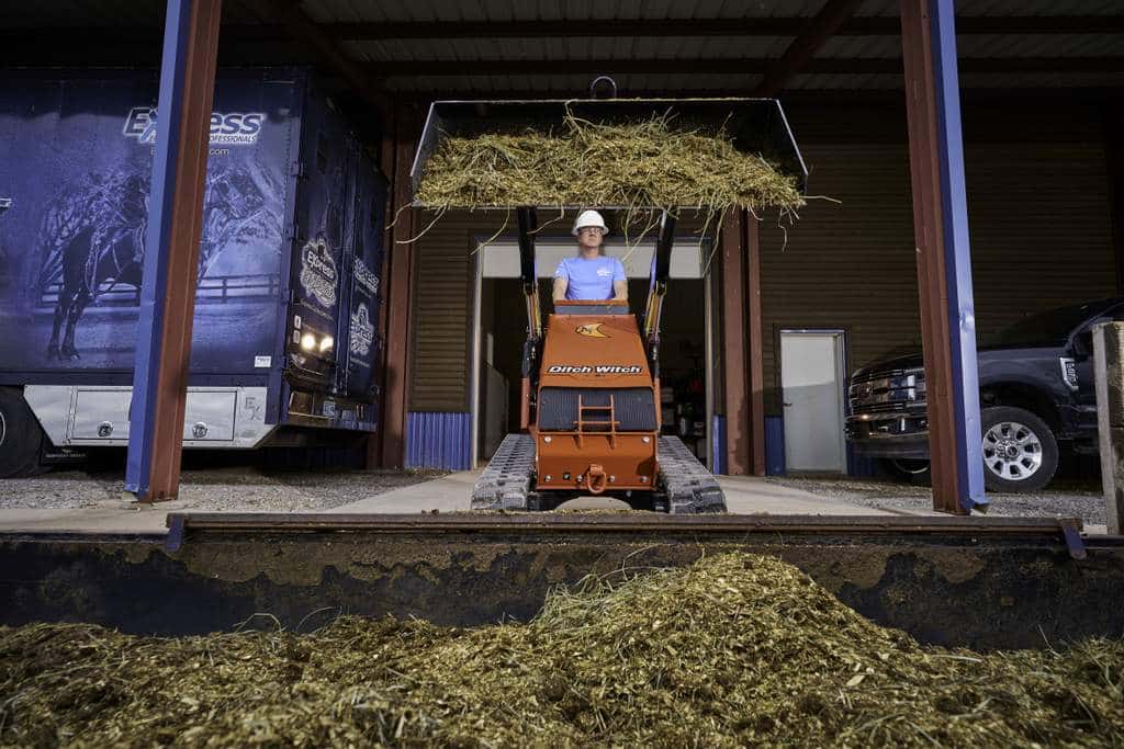 Ditch Witch's SK1000 Stand-On Skid Steer lifting dirt and hay