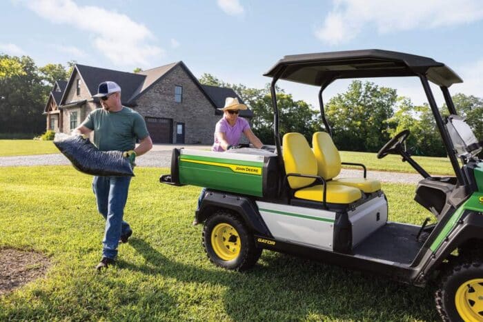 Gator GX John Deere Utility Vehicle man moving bag of mulch